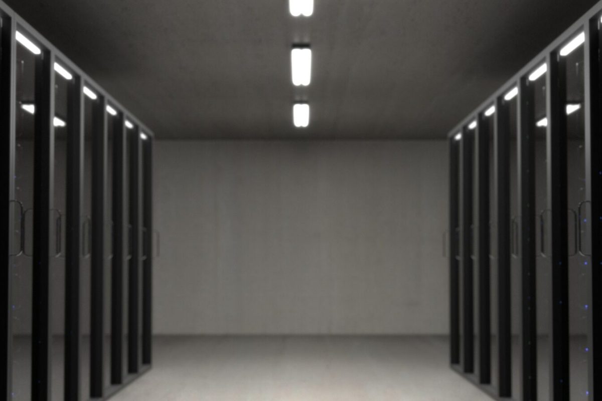 Datacenter with black racks and grey cement stone walls.